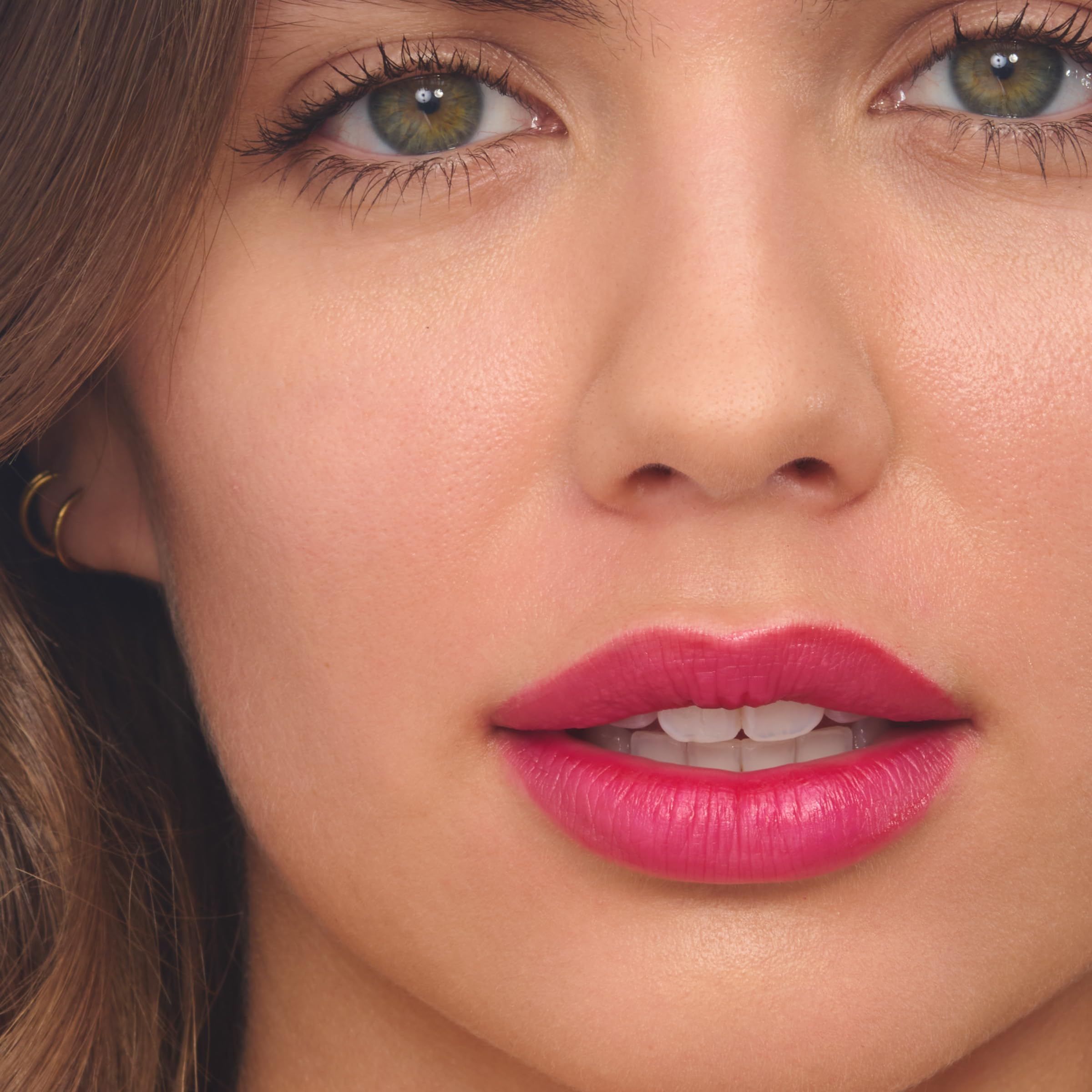 Primo piano di labbra con rossetto rosa. Occhi verdi.