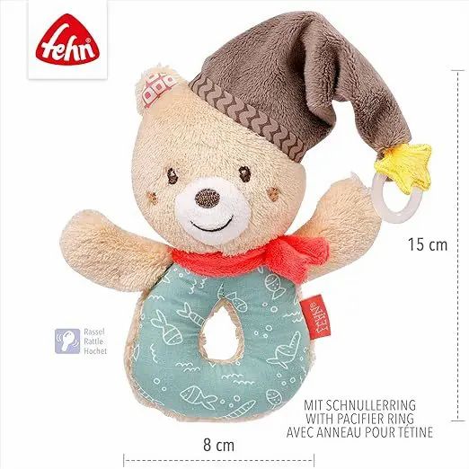 Sonaglio orsetto in peluche con cappello, sciarpa rossa e anello blu. Dimensioni: 8x15 cm. Testo: Con anello portaciuccio.