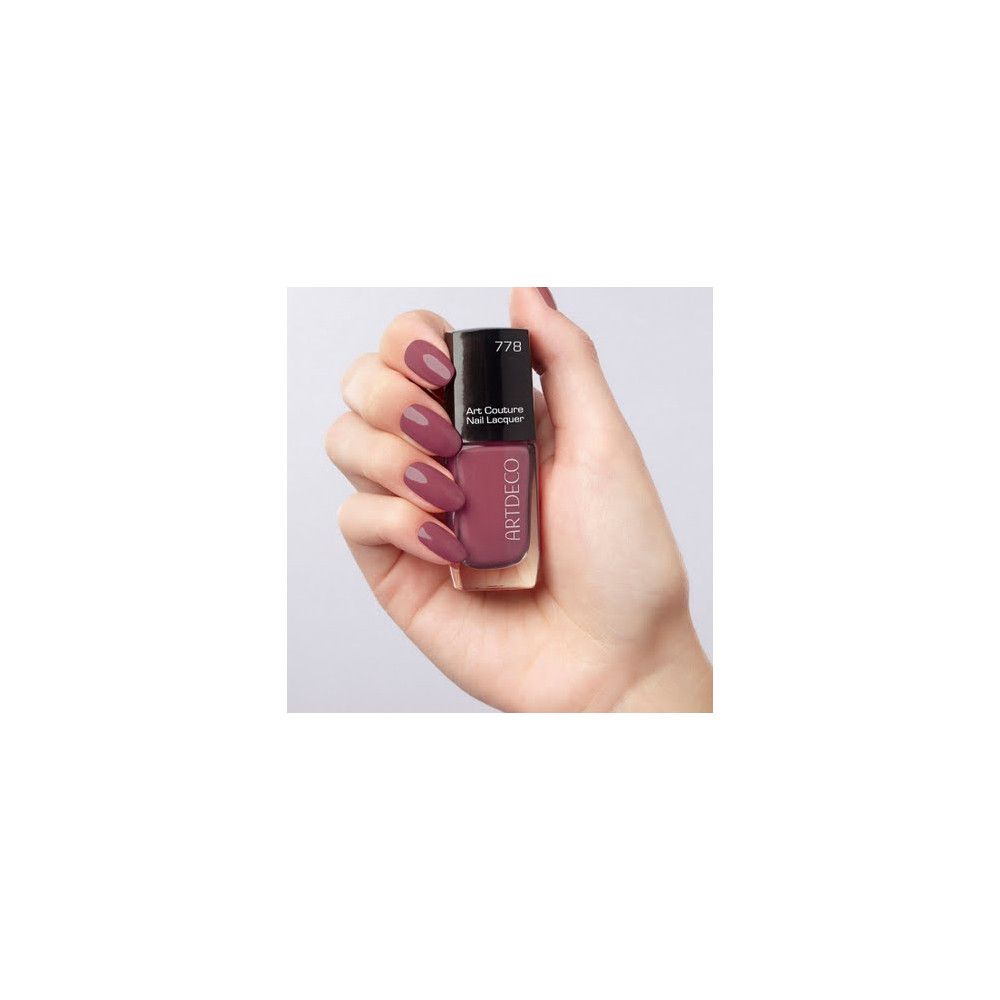 Flacone di smalto per unghie, colore 778, tenuto in mano. Art Couture Nail Lacquer. Tonalità rosa-viola. Tappo nero.