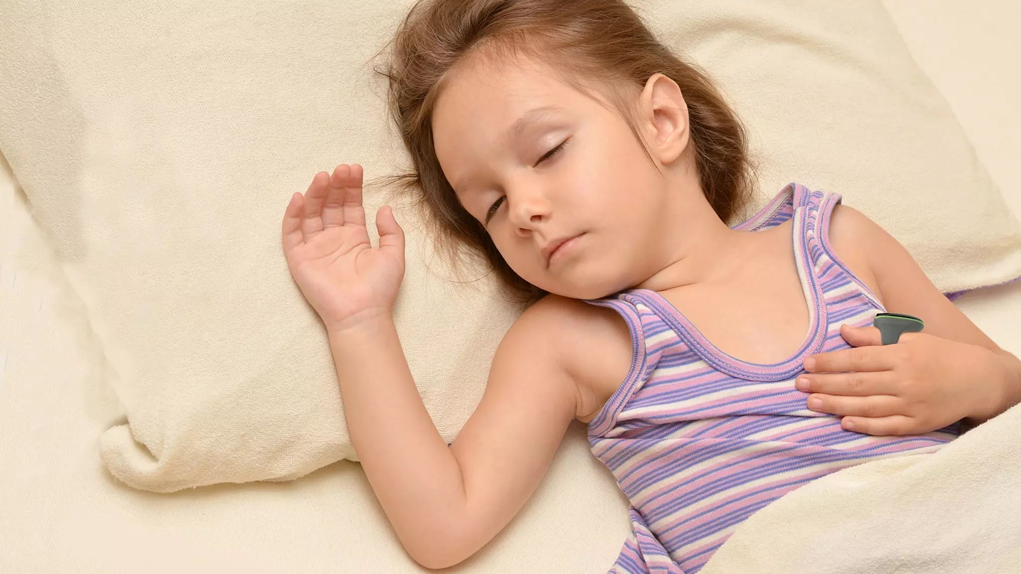 Bambina che dorme con un termometro sotto il braccio.