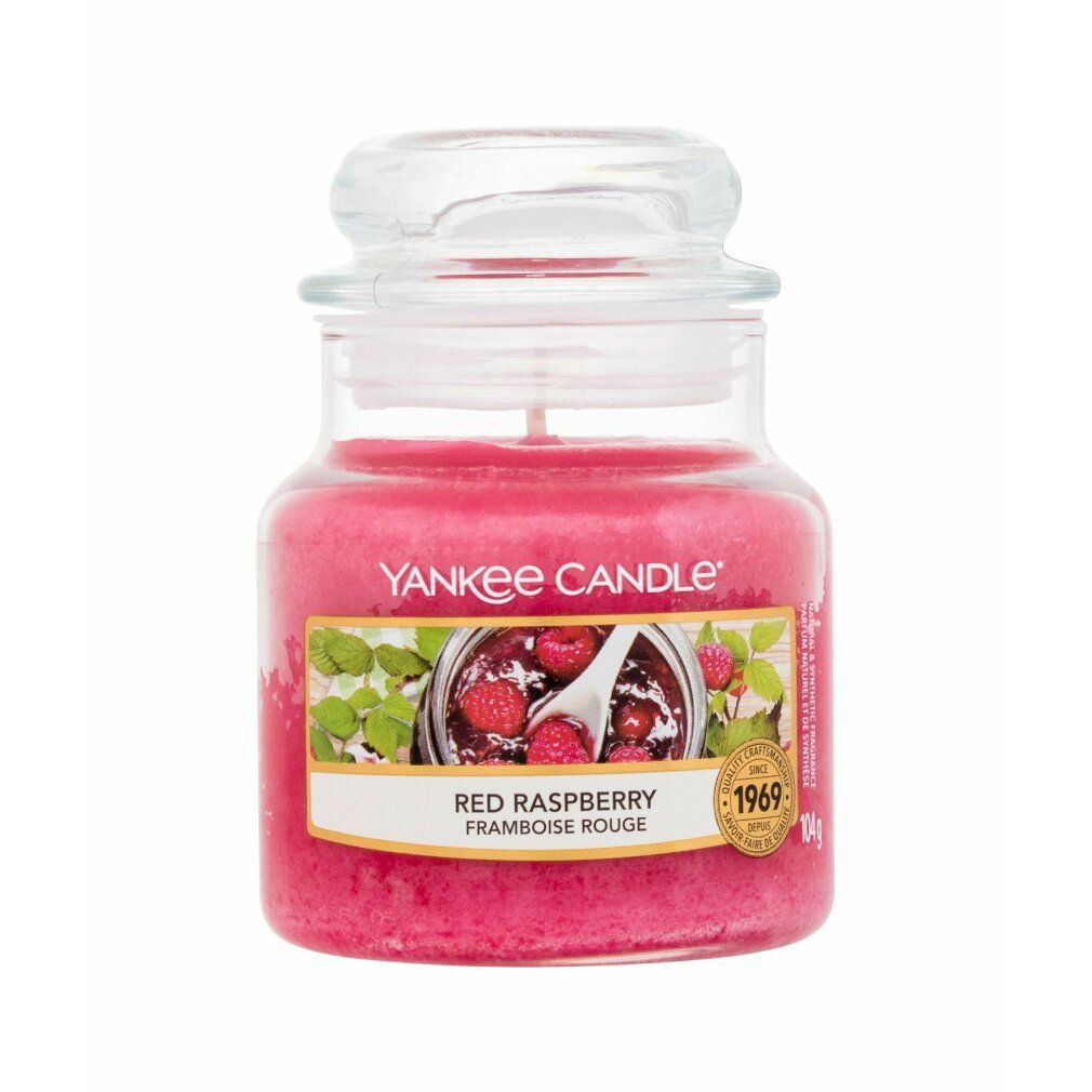 Candela rosa in barattolo con coperchio. Scritta: Yankee Candle Red Raspberry. Immagine di lamponi.