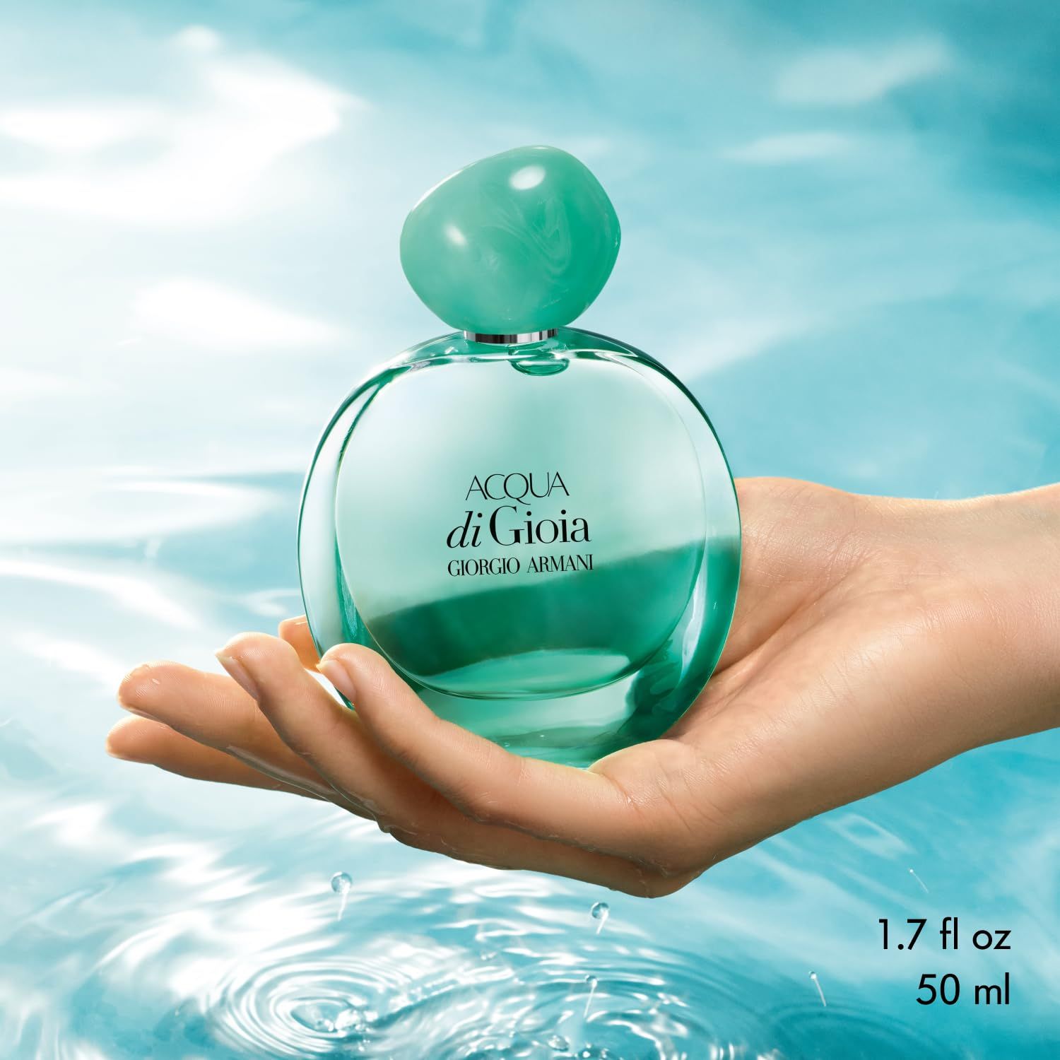 Flacone Acqua di Gioia con tappo verde in una mano. Testo: Acqua di Gioia, Giorgio Armani, 1.7 fl oz 50 ml.