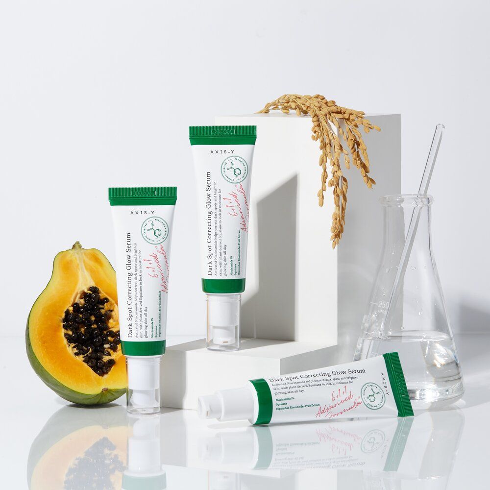 Tre tubetti e decorazioni. Scritta: Dark Spot Correcting Glow Serum. Marchio: AXIS-Y. Prodotto in tubetti bianchi con tappo verde.