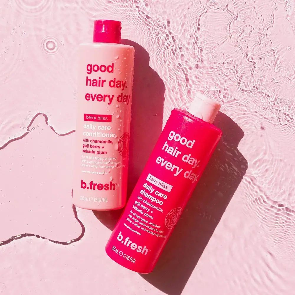 Due flaconi di shampoo su superficie rosa. Scritta: good hair day. every day. berry bliss daily care shampoo. b.fresh.