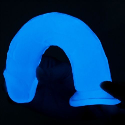 Dildo blu fluorescente curvo. Tenuto da una mano.