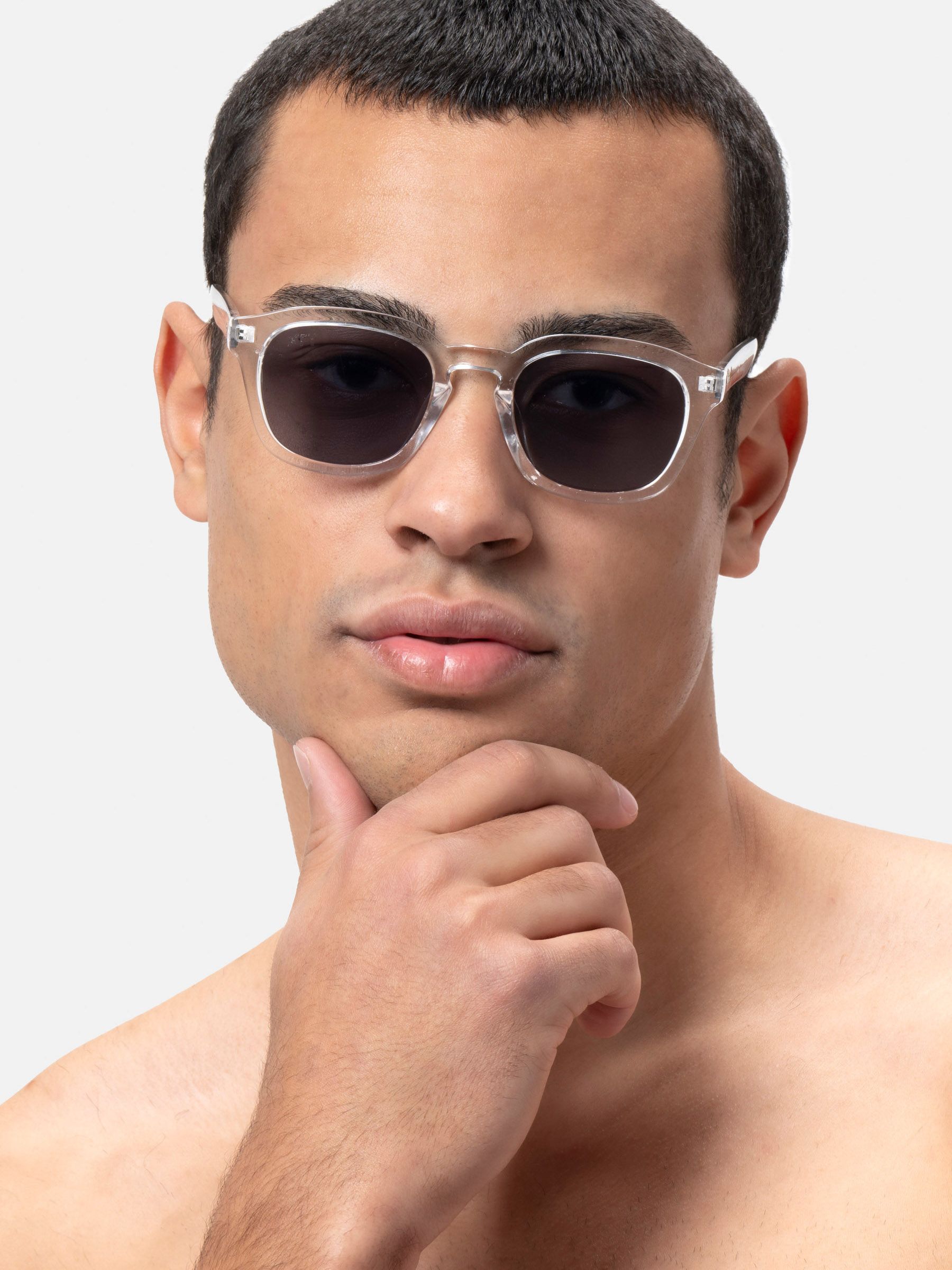 Primo piano: uomo con occhiali da sole con montatura trasparente e lenti scure. Forma squadrata.