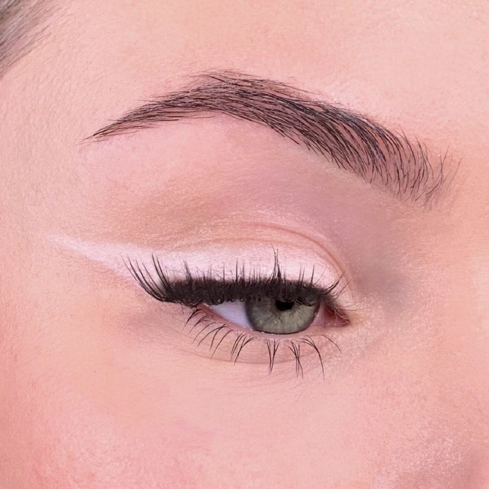 Occhio con ombretto rosa. Linea rosa sulla palpebra. Sopracciglia e ciglia visibili.