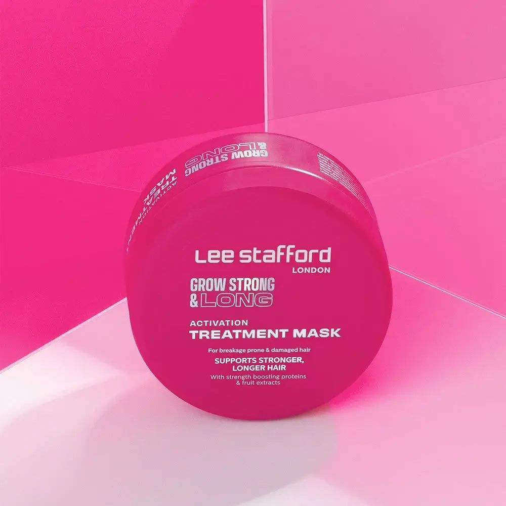 Un vasetto rosa della Lee Stafford Grow Strong & Long Activation Mask è posizionato su una superficie rosa.
