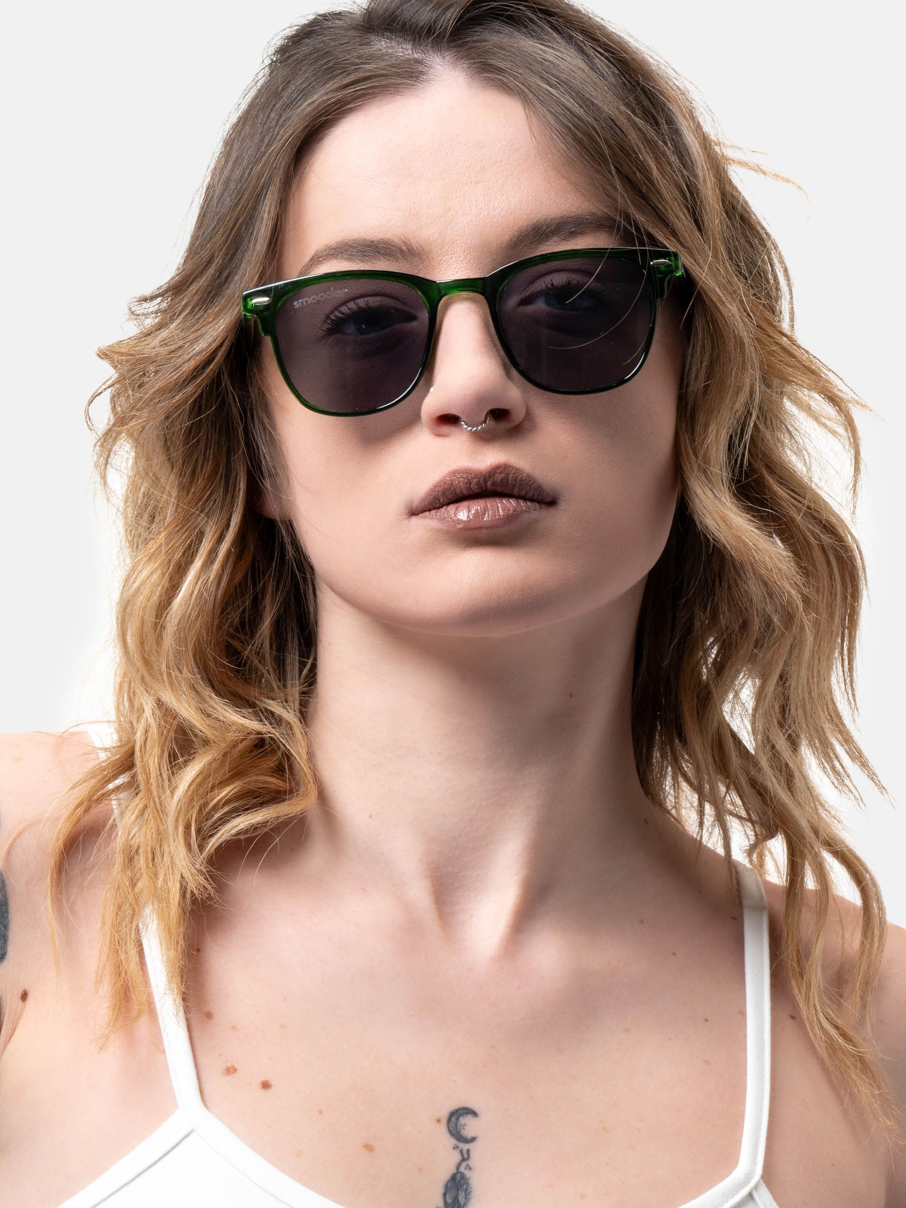 Persona indossa occhiali da sole verdi con lenti scure. Il marchio 'Smooder' è visibile.