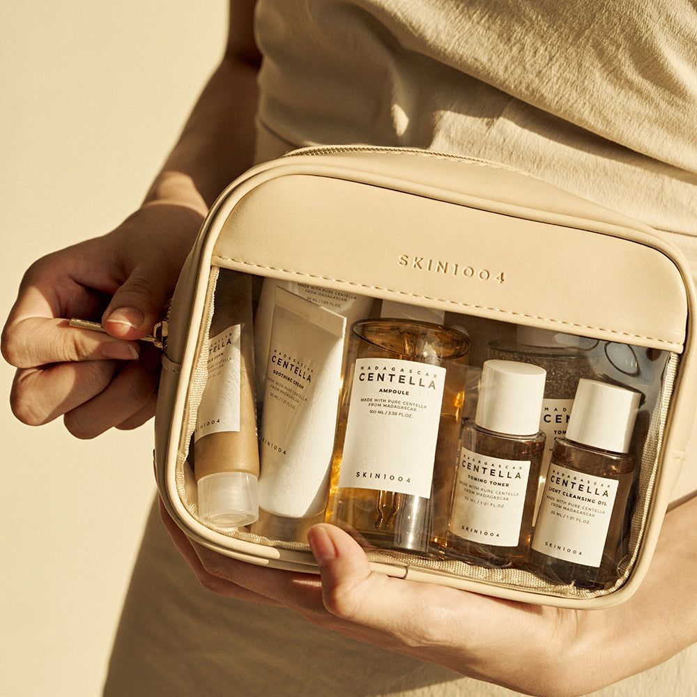 Pochette cosmetica beige con prodotti. Include creme, toner e sieri. Prodotti SKIN1004.