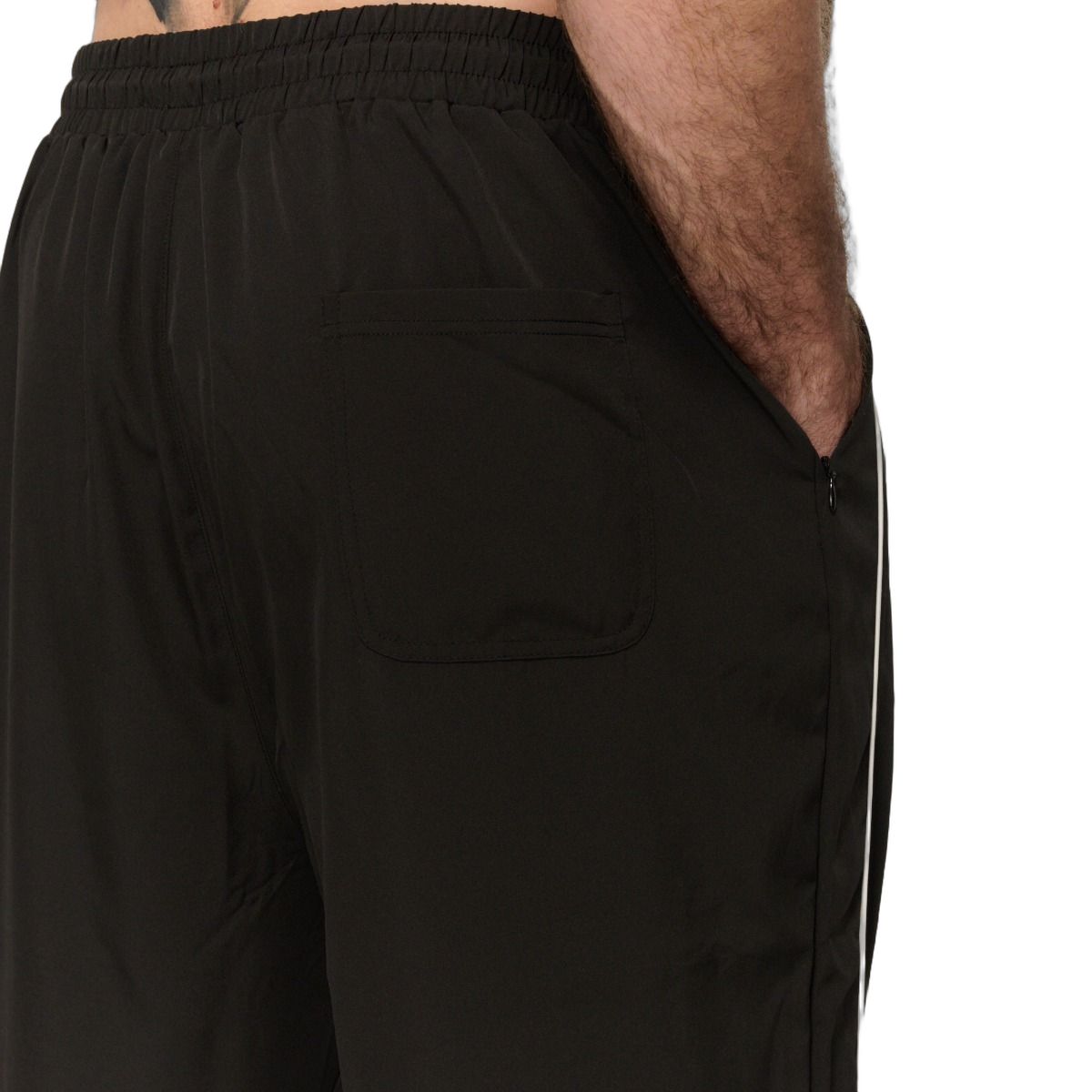 Vista posteriore di un pantalone da jogging nero da uomo con strisce laterali bianche.
