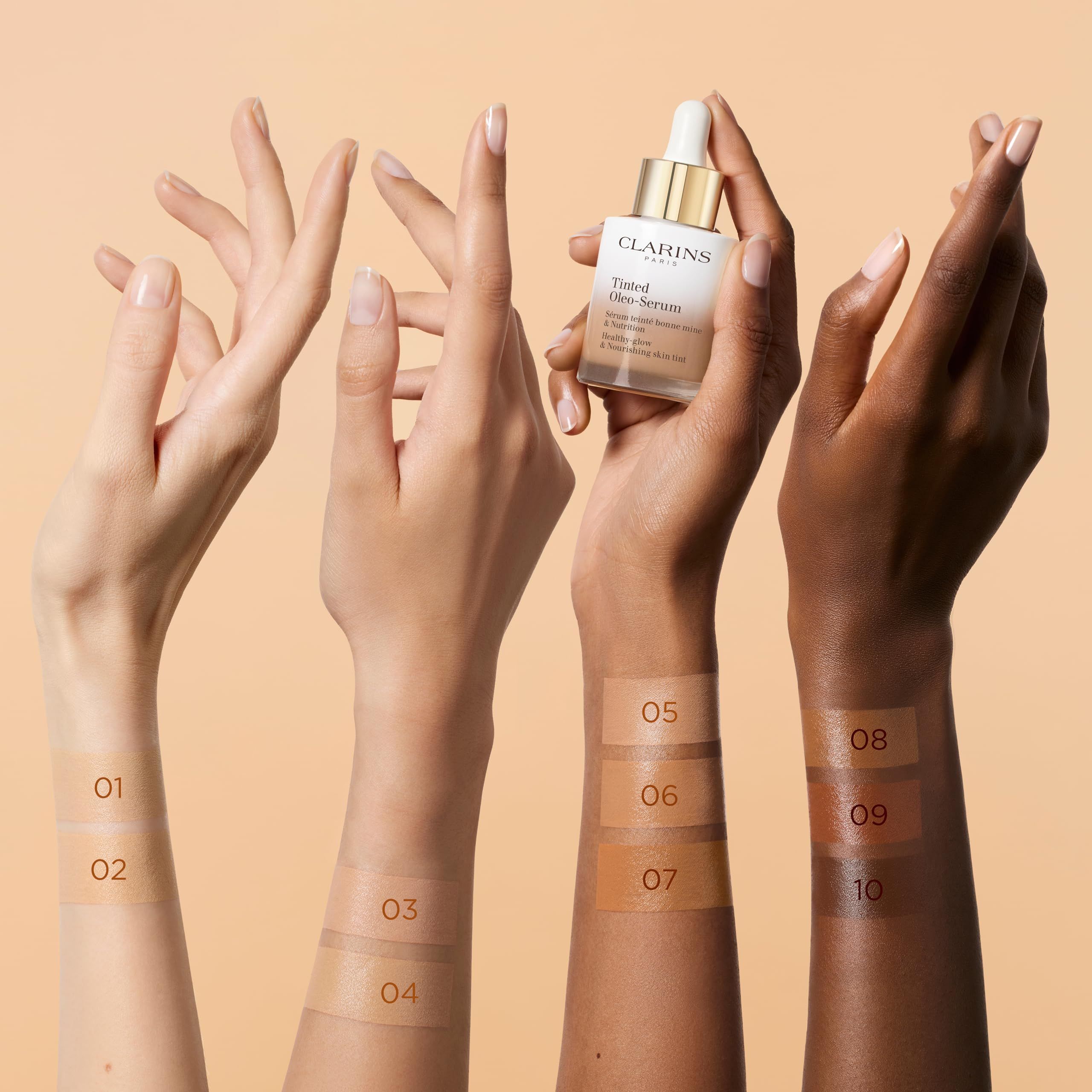 Mani con campioni di colore. Flacone con pipetta. Scritta: Clarins Paris, Tinted Oleo-Serum. Tonalità della pelle.