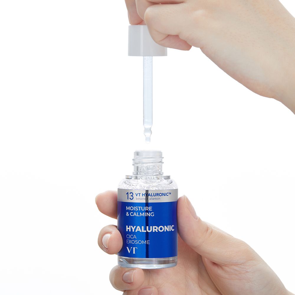 Mani che tengono un flacone di siero e un applicatore. Flacone con etichetta blu. Testo: Hyaluronic Cica Exosome, VT.