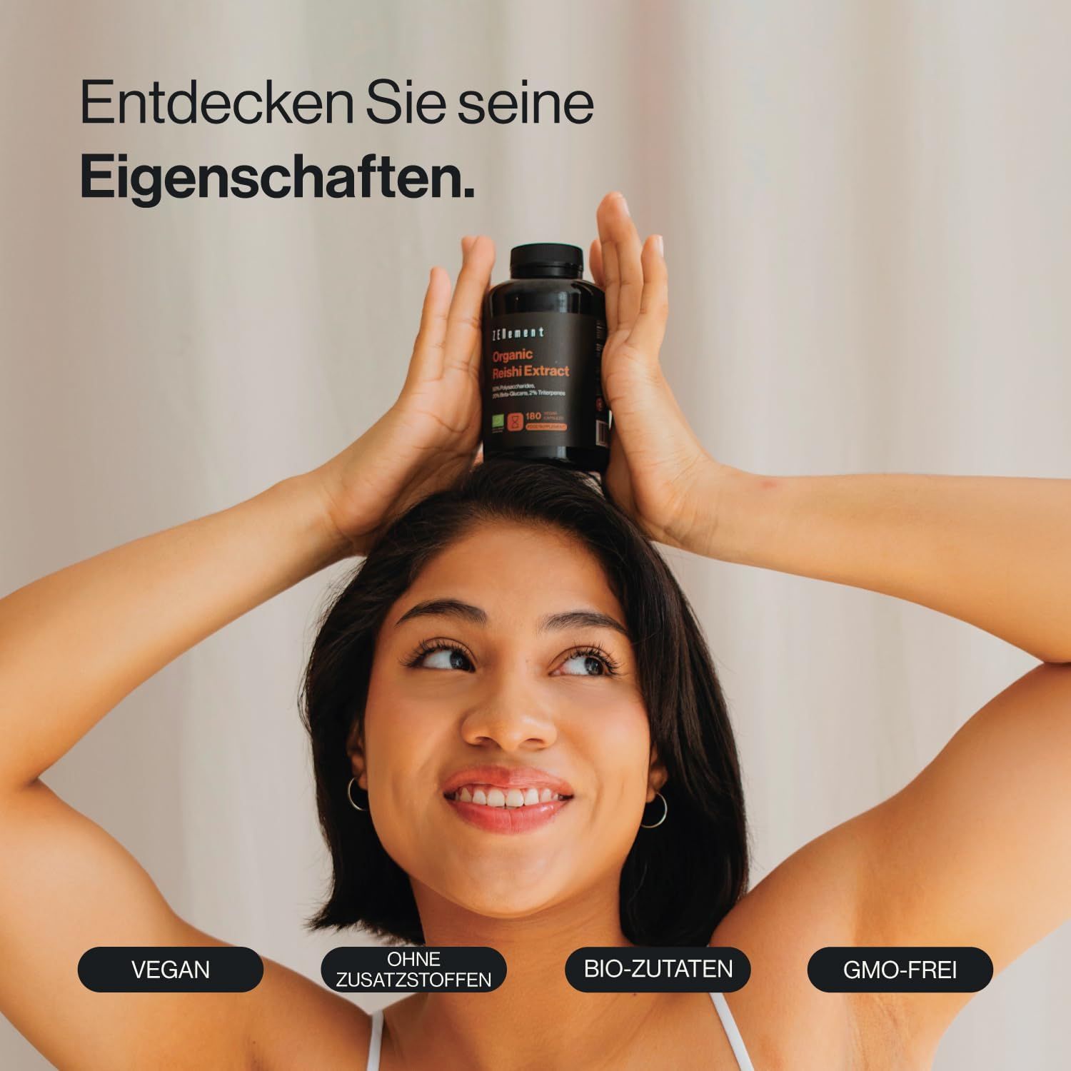 Una donna tiene una bottiglia di capsule sulla testa. La bottiglia riporta la scritta "Zenement Bio Reishi Extrakt".