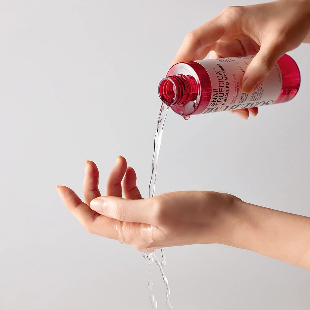 Una mano versa un liquido limpido da una bottiglia rossa nel palmo.