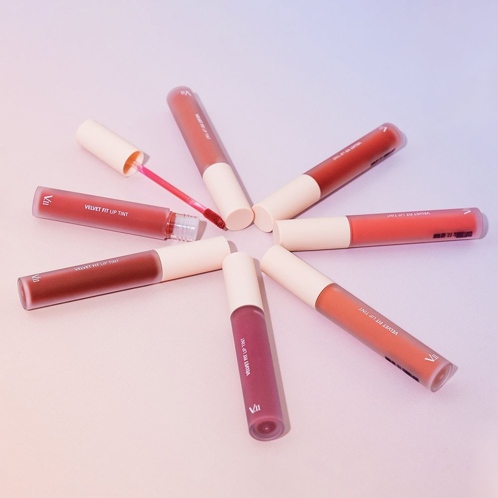 Sette tinte labbra Ruby Pink, effetto velluto, disposte a stella. Flacone aperto con applicatore. Scritta: VELVET FIT LIP TINT.