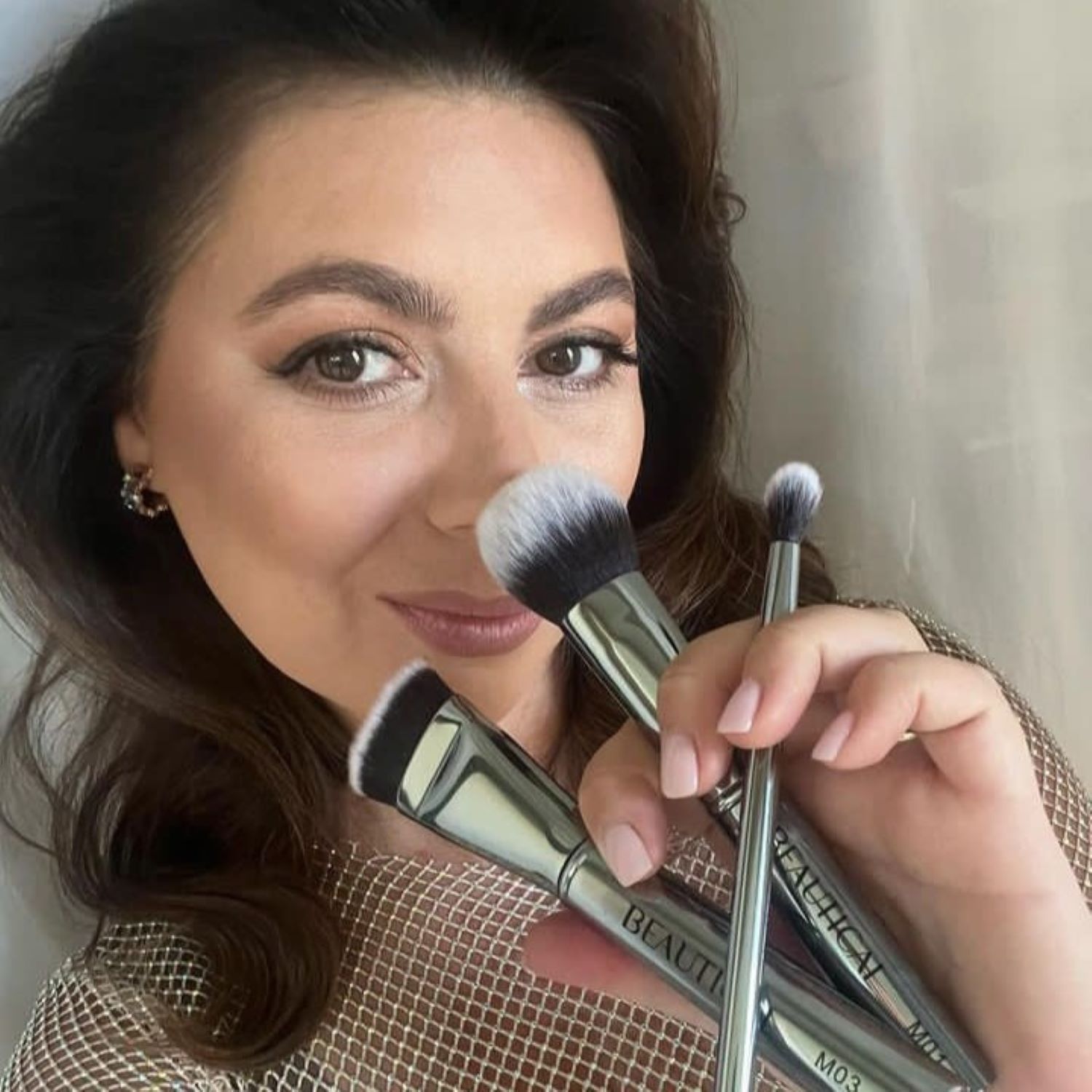 Donna che tiene tre pennelli. Il marchio BEAUTICAL è visibile. Manici argentati.