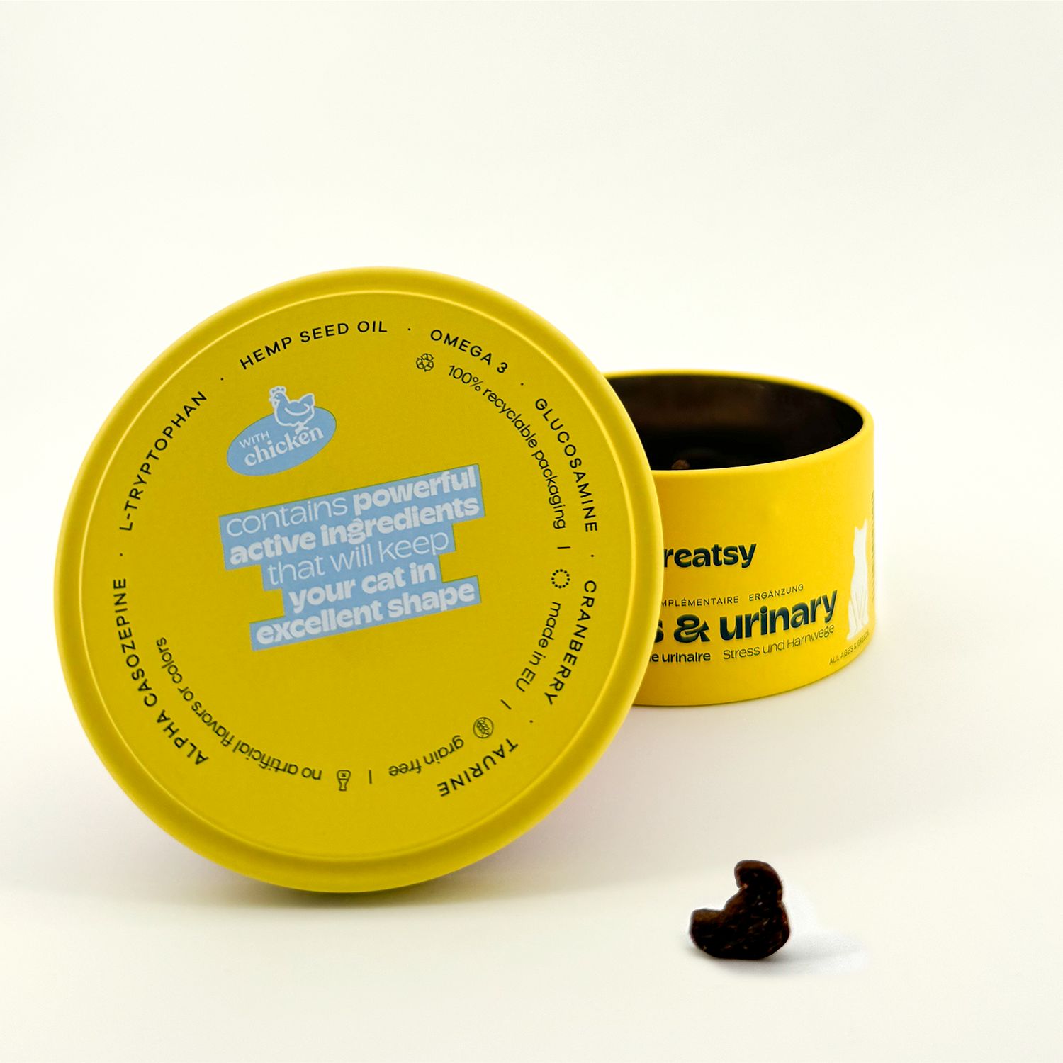 Barattolo giallo con scritta. Coperchio aperto. Snack marrone a forma di gatto.
