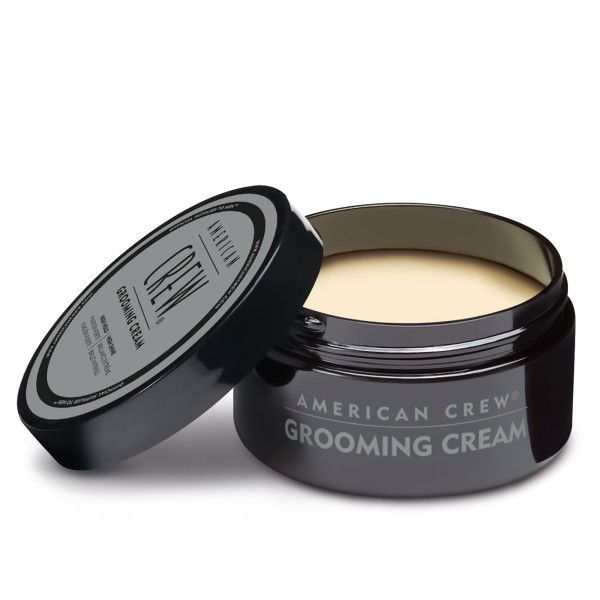 Barattolo nero con coperchio. Sul coperchio è scritto "AMERICAN CREW GROOMING CREAM". Barattolo aperto, crema visibile.