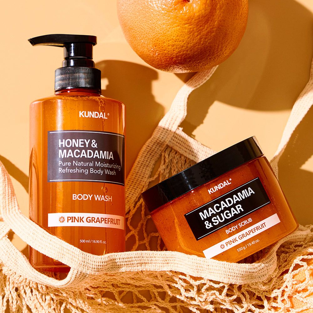 Kundal Body Wash e Body Scrub Macadamia e Pompelmo Rose in flaconi arancioni.