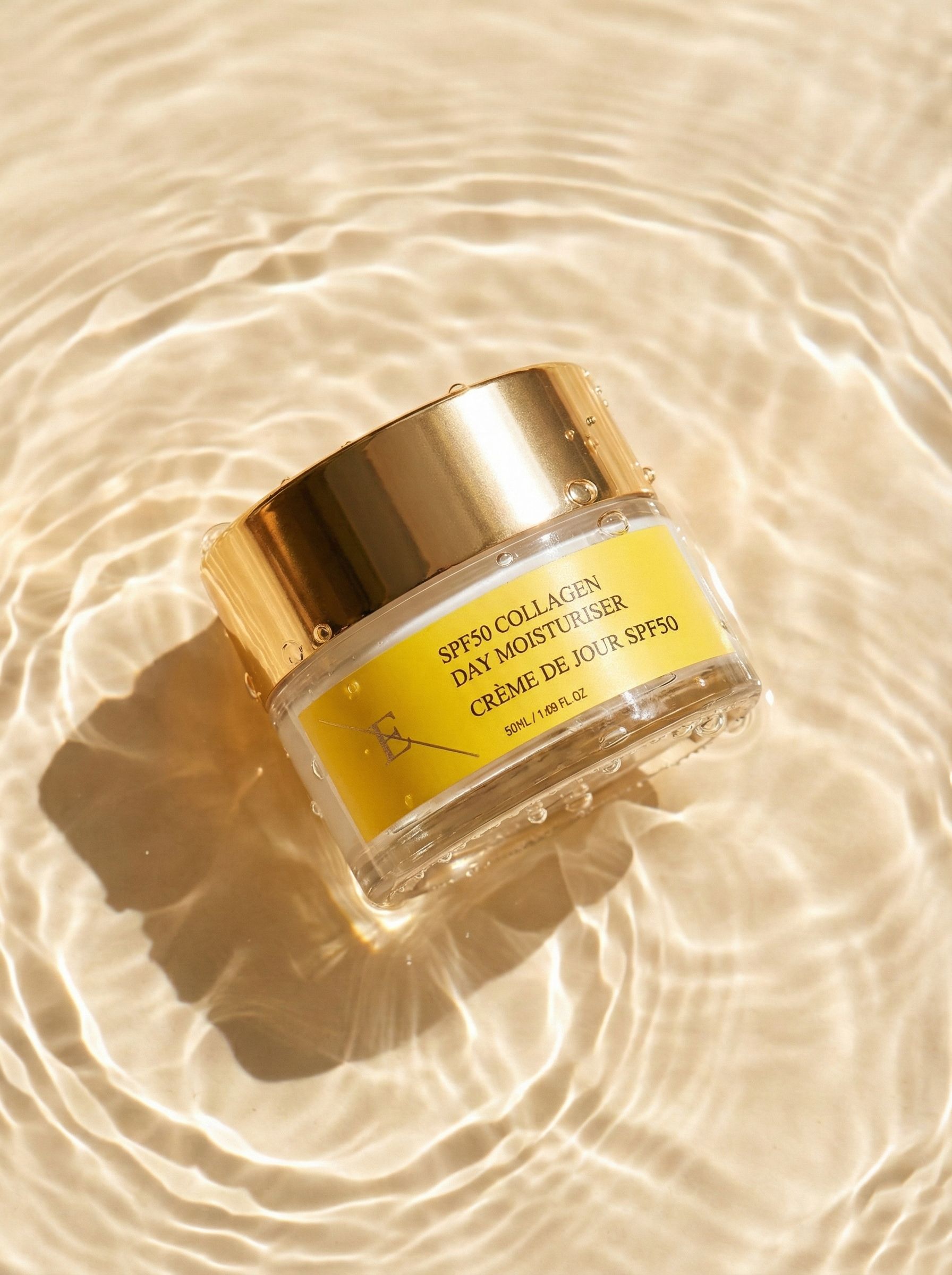 Vasetto di crema con coperchio dorato nell'acqua. Etichetta gialla con testo: SPF50 Collagen Day Moisturiser, Crème de Jour SPF50. Increspature.