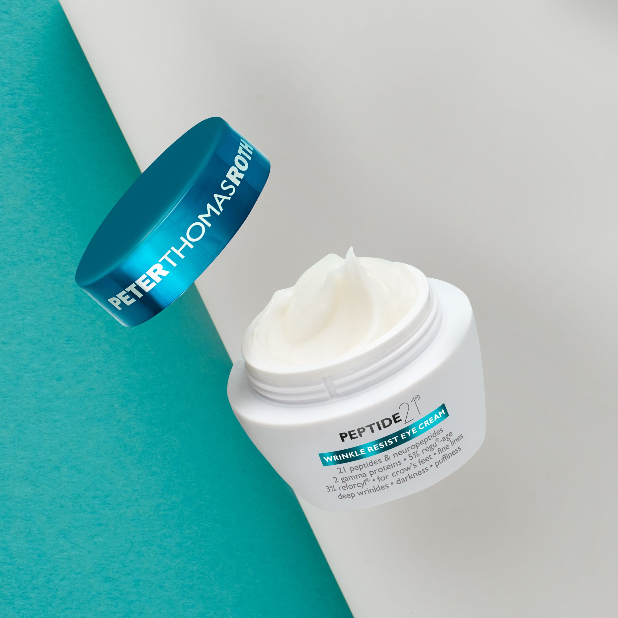 Peter Thomas Roth Peptide 21® Wrinkle Resist Eye Cream. Vasetto aperto, crema e coperchio. Su sfondo blu e bianco.
