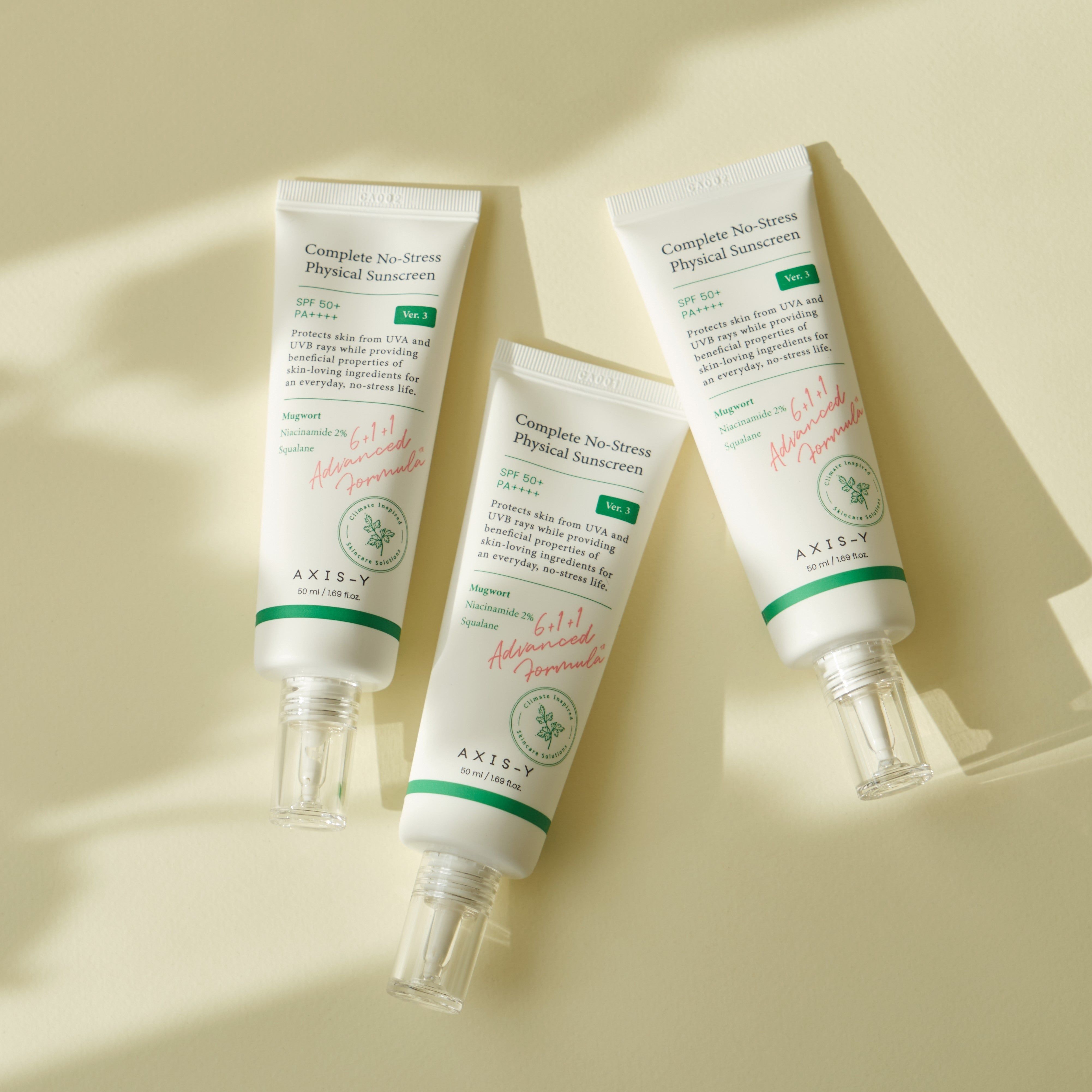 Tre tubetti AXIS-Y Complete No-Stress Physical V.3 SPF 50. Bianchi con dettagli verdi. Su sfondo chiaro.