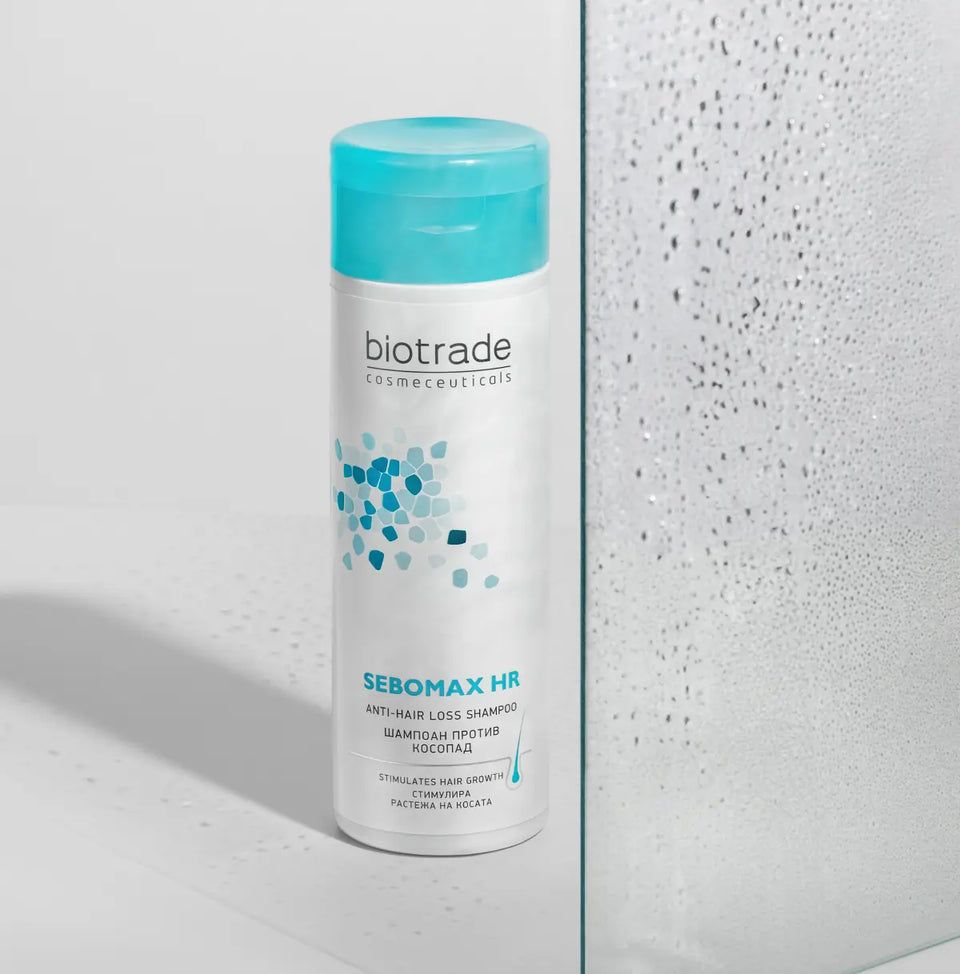 Biotrade Sebomax HR Shampoo, flacone bianco, tappo blu. Testo: Sebomax HR, shampoo anticaduta. Motivi blu e turchese.