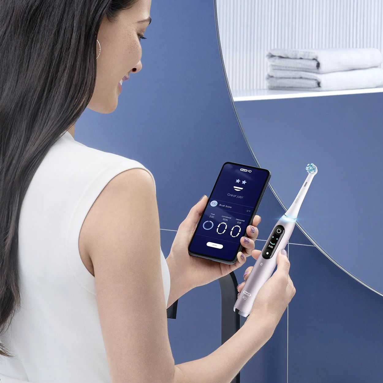 Donna con spazzolino e smartphone. L'app Oral-B è visibile sullo schermo dello smartphone.