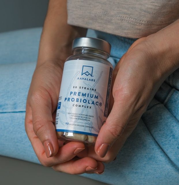 Mani che tengono un contenitore di capsule probiotiche Aavalabs.