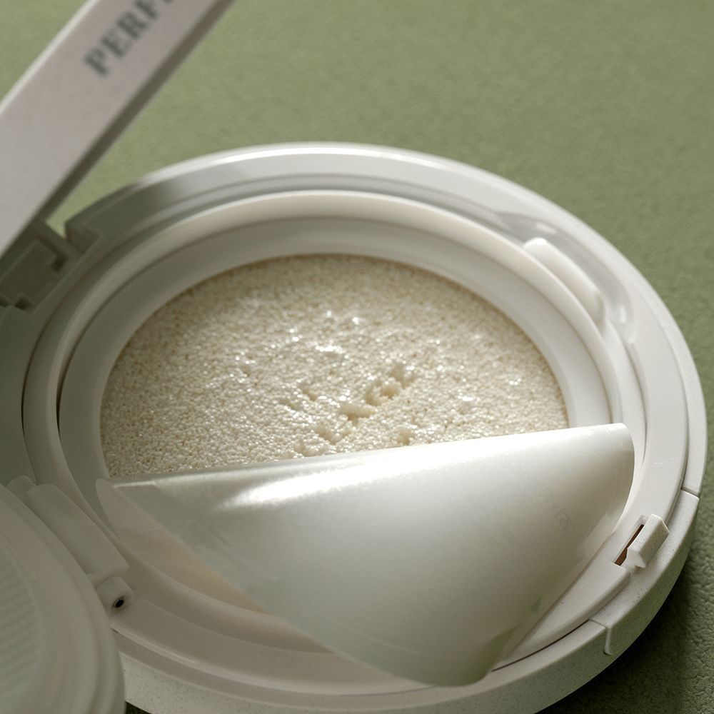 Contenitore compatto bianco per trucco con spugna e applicatore. Il coperchio è aperto. Il nome del marchio è visibile sulla spugna.