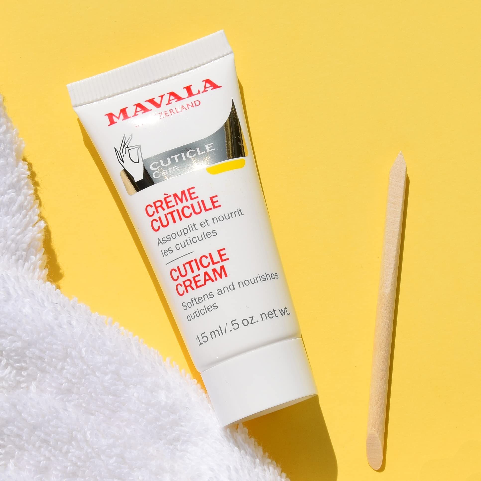 Tubo di Crème Cuticule, 15 ml, accanto a bastoncino di legno. Testo: Crème Cuticule, 15 ml. Marchio: Mavala Switzerland. Su sfondo giallo.