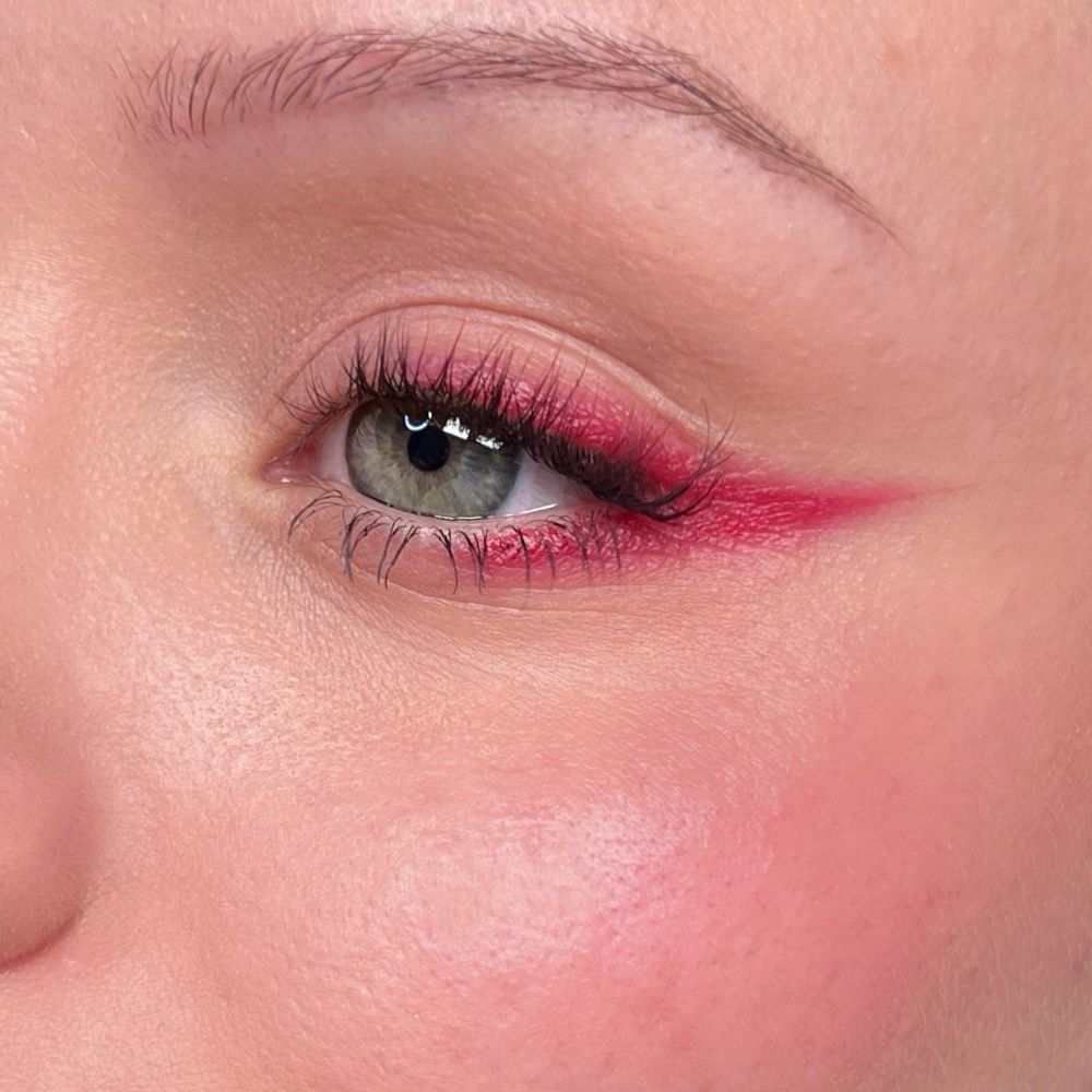 Primo piano di un occhio con eyeliner rosso e mascara. Tonalità della pelle.