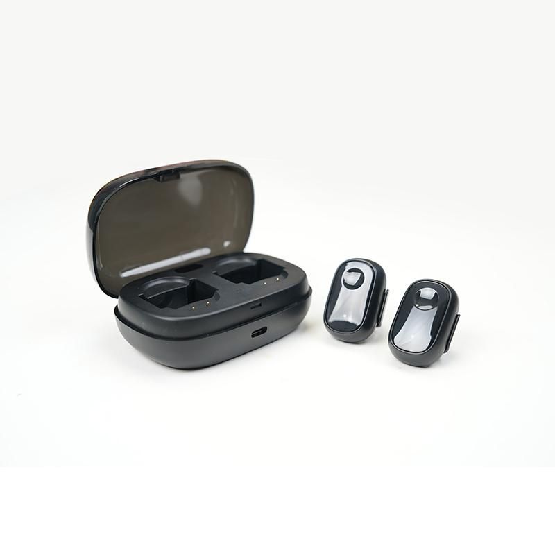 Dispositivo nero ovale con due aperture e due auricolari neri. Gli auricolari sono accanto alla custodia di ricarica aperta.