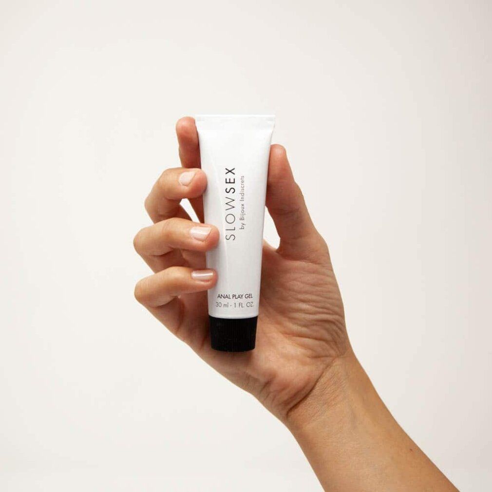 Mano che tiene un tubo bianco. Scritta: SLOW SEX by Bijoux Indiscrets. ANAL PLAY GEL.