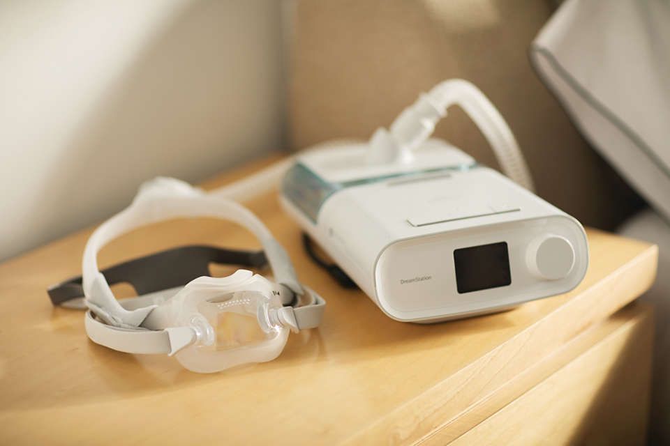 Maschera Philips CPAP DreamWear e dispositivo CPAP su un comodino.