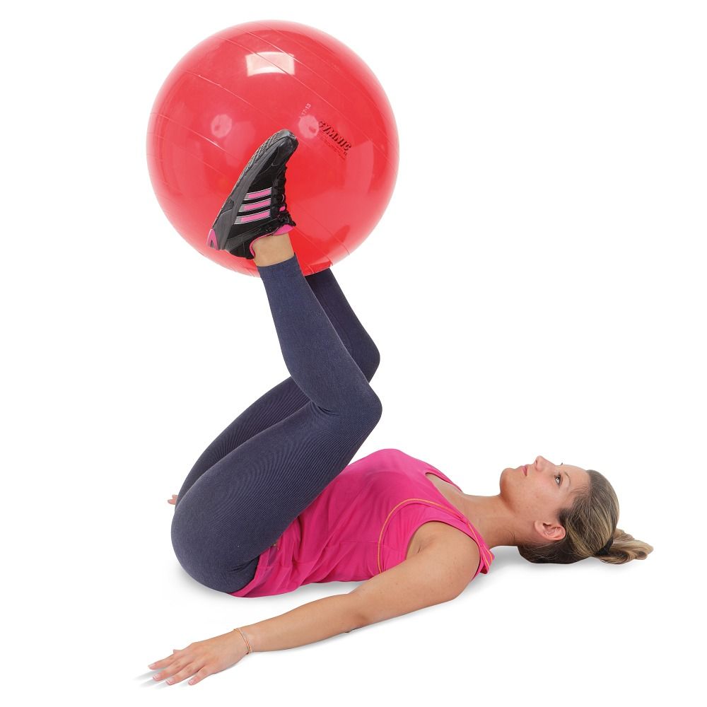 Una donna è sdraiata sulla schiena, tiene un pallone da ginnastica rosso tra i piedi.