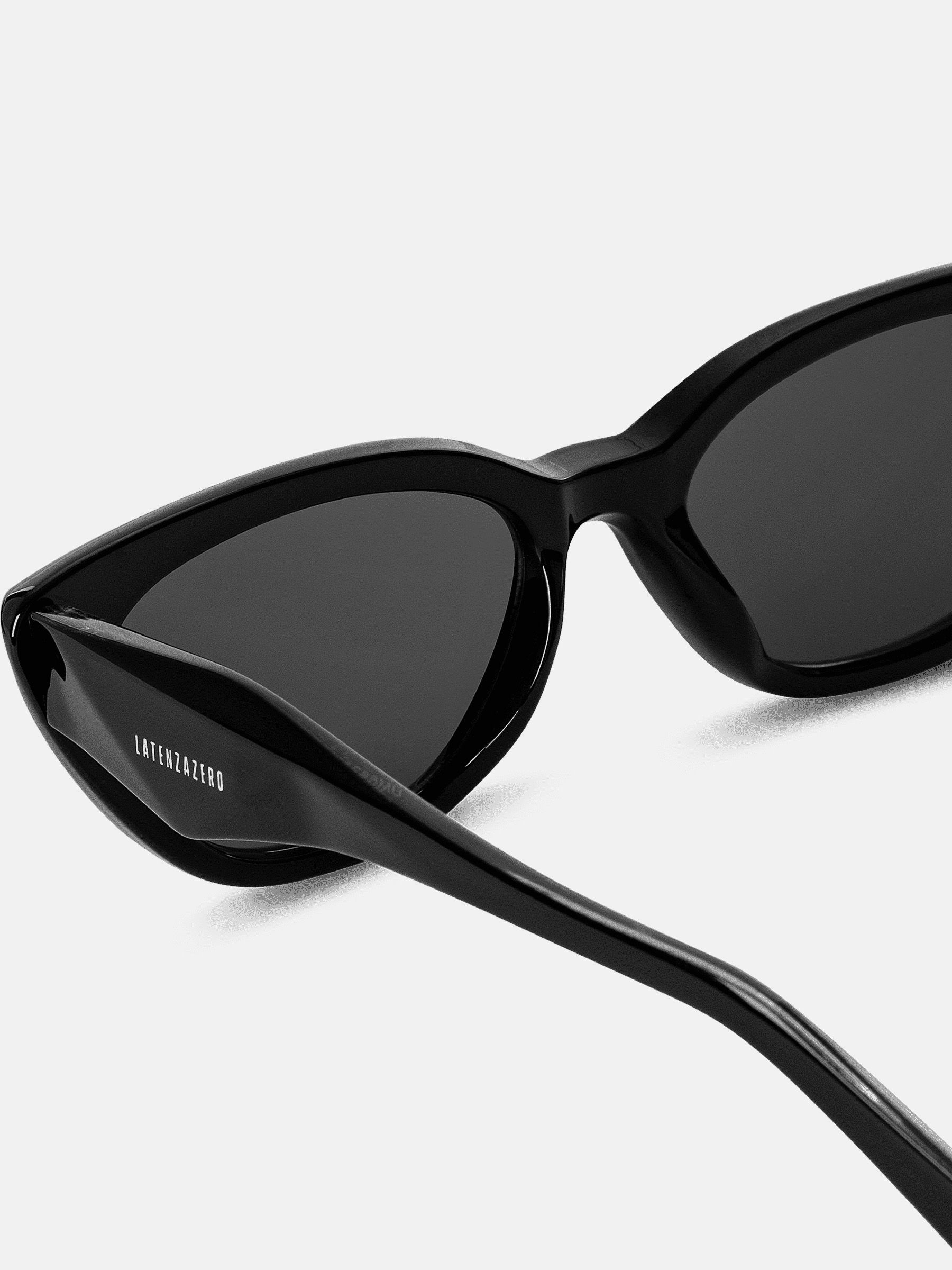 Primo piano degli occhiali da sole neri. Logo Latenzazero sull'asta. Montatura lucida, lenti scure.