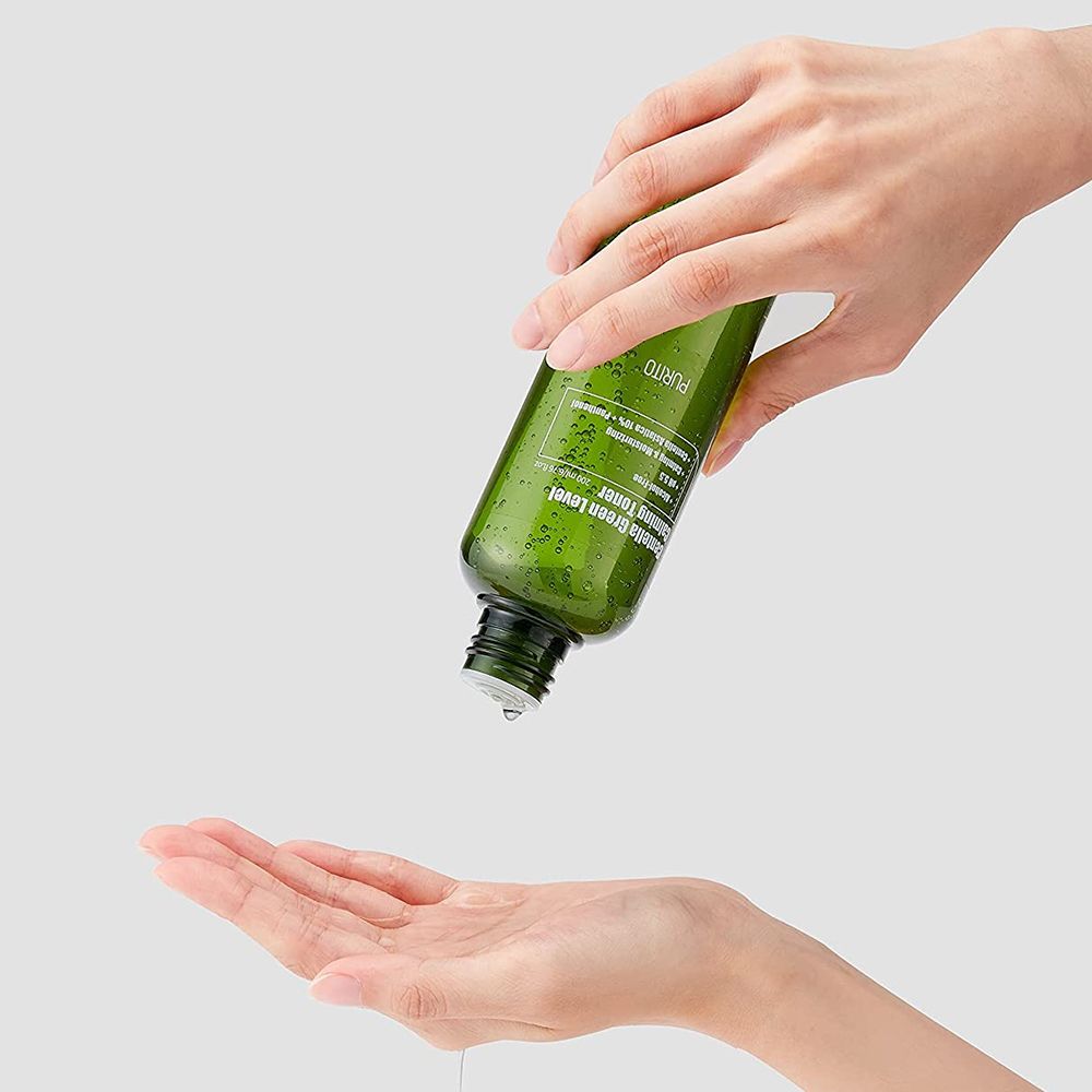 Mani che tengono un flacone verde. Il liquido viene versato nella mano. Scritta: Centella Green Level Calming Toner.