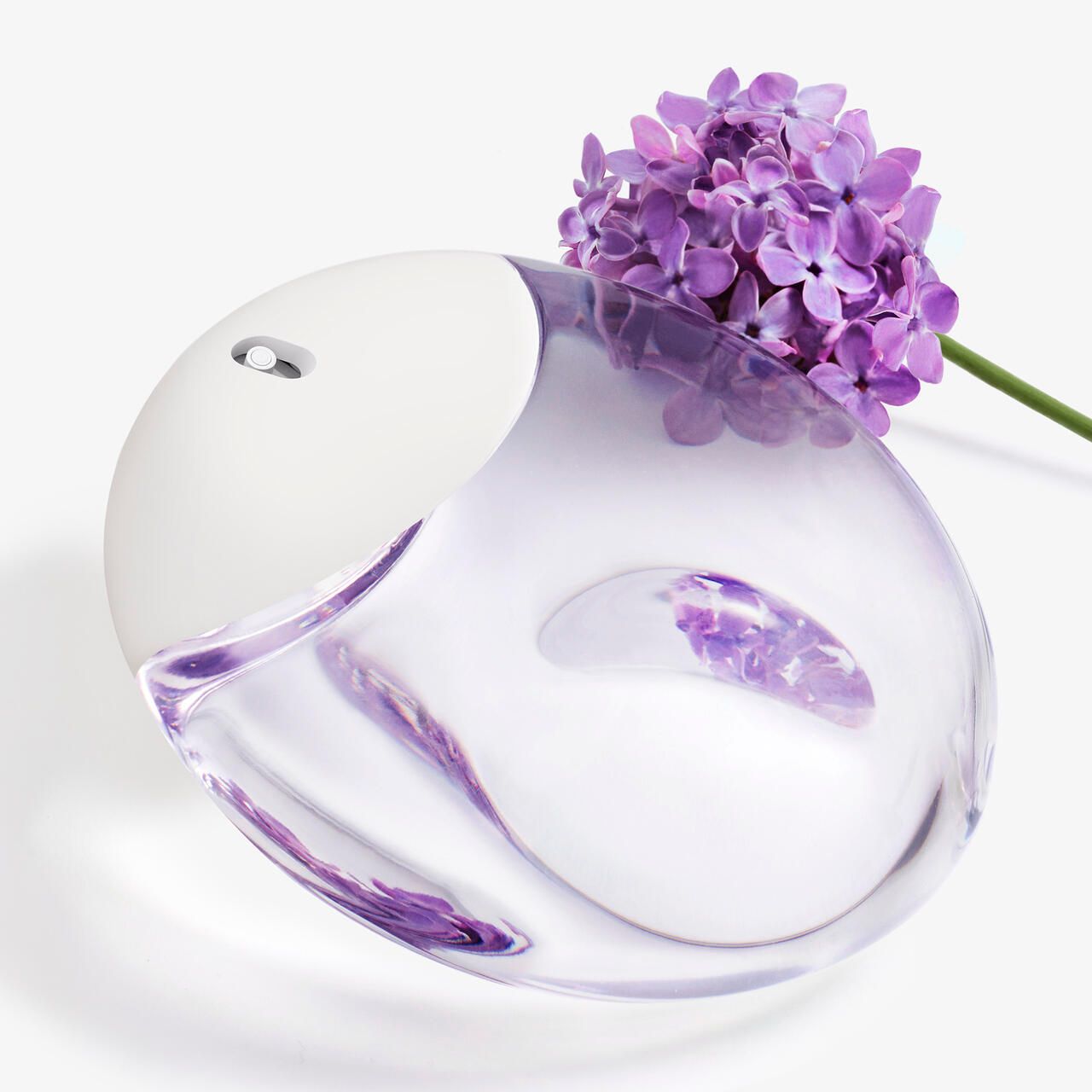 Flacone rotondo con tappo bianco, riempito di liquido viola. Fiori viola accanto.
