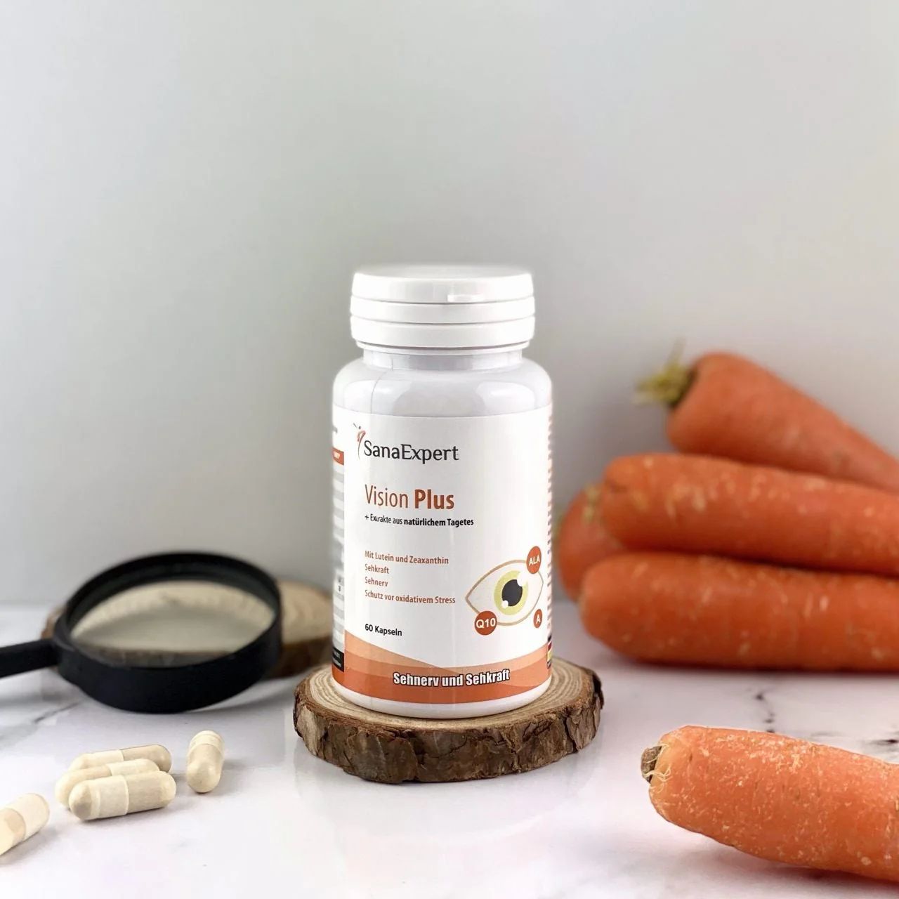 Flacone SanaExpert Vision Plus, carote, lente d'ingrandimento e capsule su legno. Prodotto per la salute degli occhi.