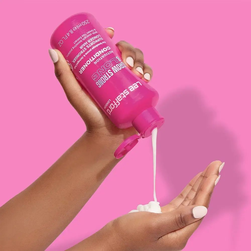 Flacone rosa di balsamo versato in una mano. Testo: Grow Strong & Long, Lee Stafford.