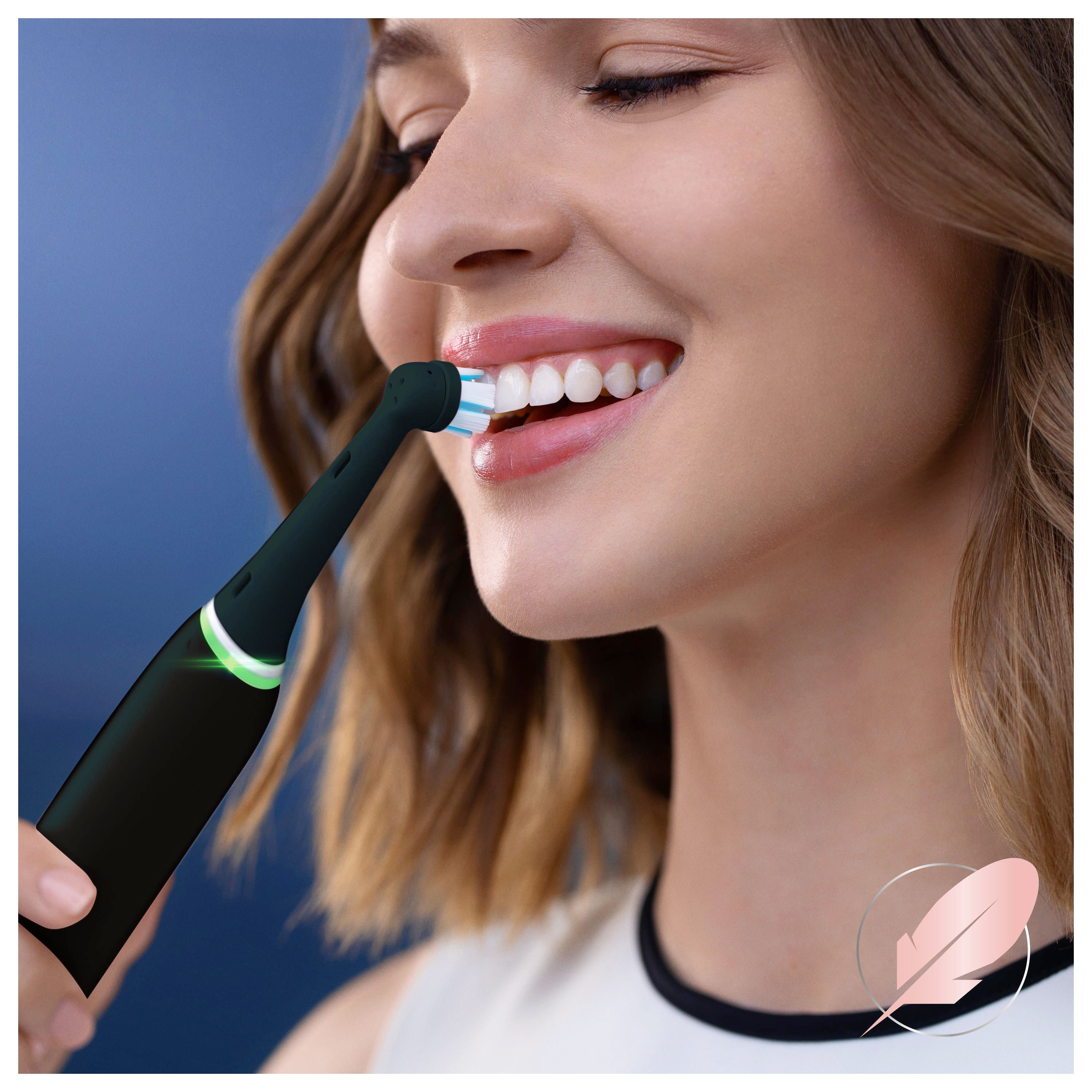 Donna che si lava i denti con spazzolino elettrico nero. Testina con setole blu.