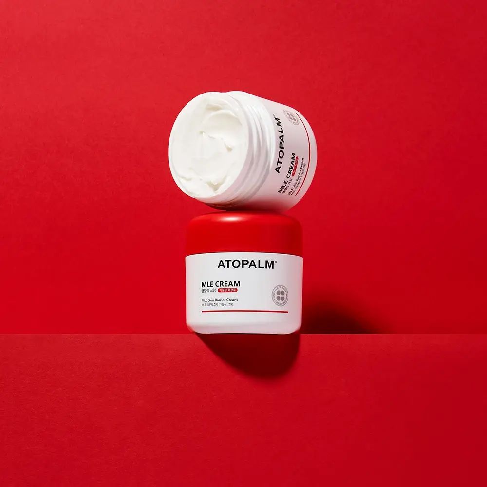 Due vasetti, uno aperto. Sfondo rosso. Scritta: ATOPALM, MLE CREAM.