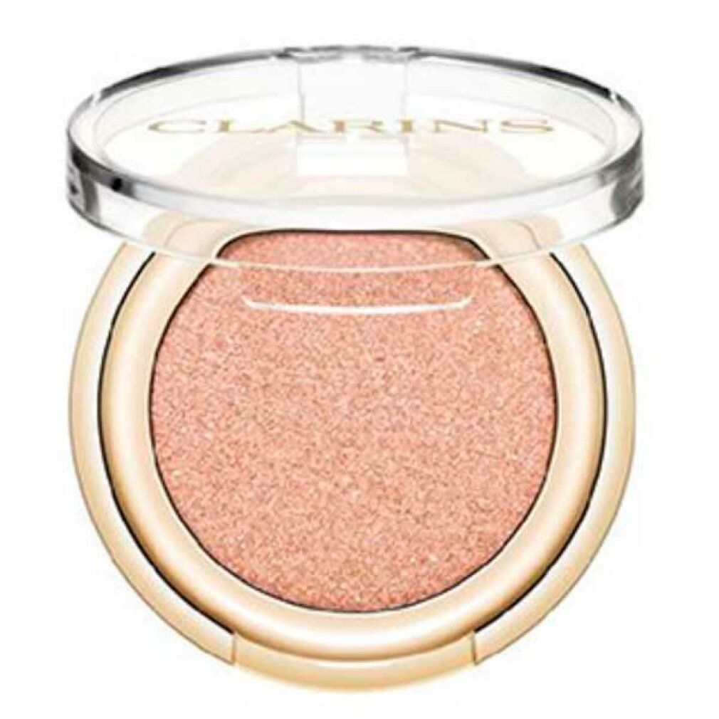 Contenitore rotondo dorato di ombretto con contenuto rosa. Il coperchio trasparente è aperto. Clarins è visibile.