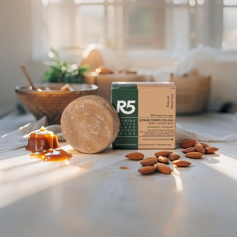 Blocco esfoliante corpo rotondo marrone vicino alla confezione. Mandorle e caramello sul tavolo. Testo sulla confezione: R5, Scrub Corpo Solido.