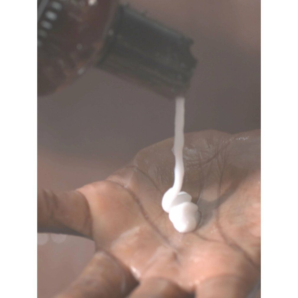 Prodotto bianco versato da un flacone in un palmo. Il prodotto è bianco e cremoso.