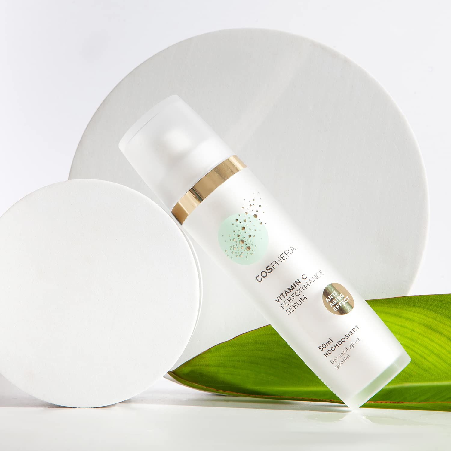Flacone bianco con erogatore a pompa, anello dorato, etichetta 'COSPHERA VITAMIN C PERFORMANCE SERUM', 50ml, 'Alta concentrazione', 'Testato dermatologicamente'.