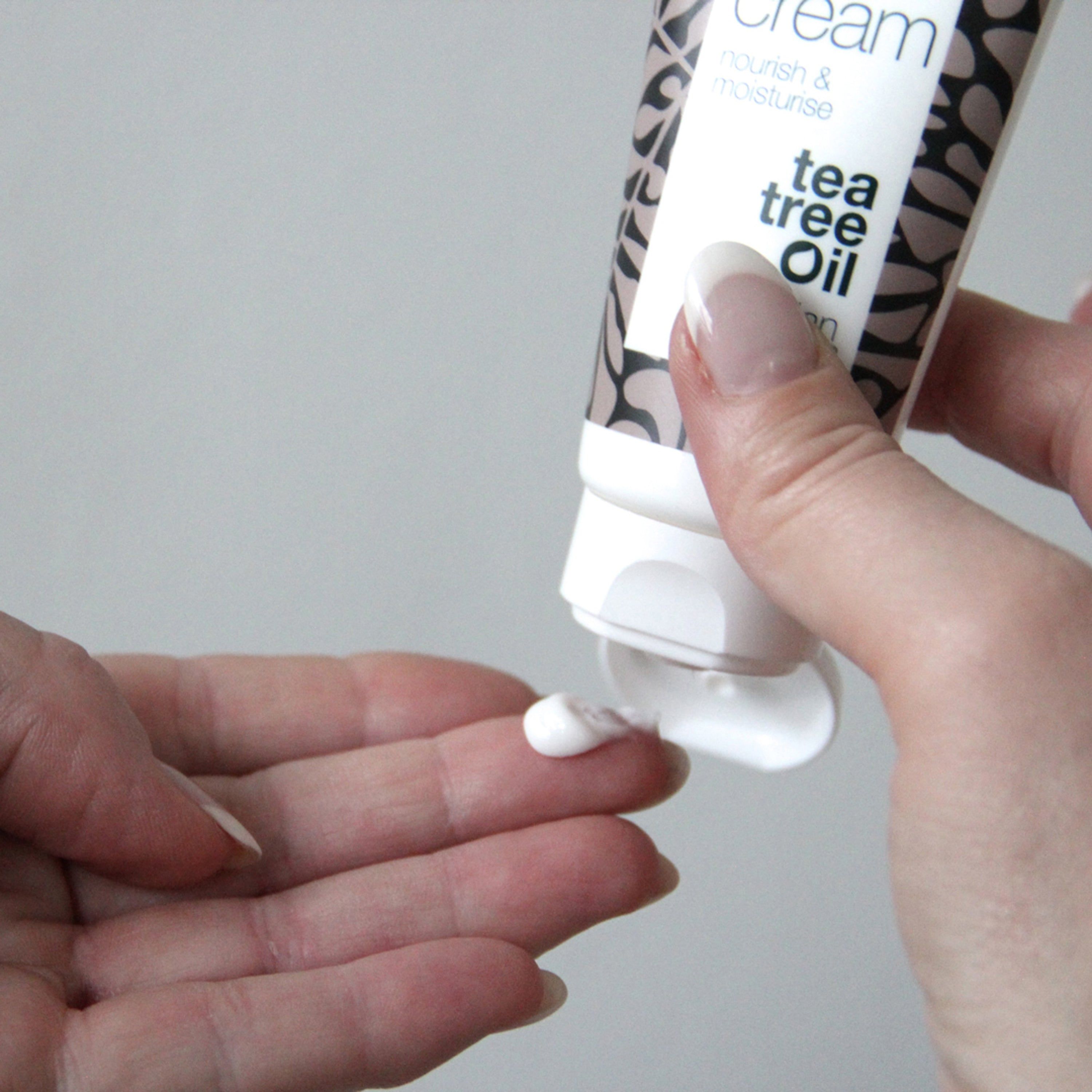 Mani con crema. Tubo con testo: face cream, tea tree oil. Marchio: Australian Bodycare. Crema spremuta dal tubo.