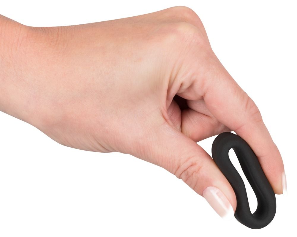 Mano che tiene un anello per pene nero e flessibile di forma ovale.
